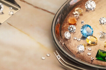 Tray with beautiful gemstones and tweezers on light table, closeup. Space for text