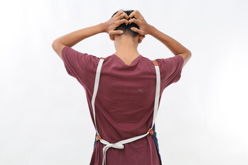 A portrait of an Asian man wearing an apron, photographed from behind, experiencing a headache and holding his head. Isolated against a white background