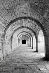 Obraz premium Historic stone archway tunnel with symmetrical perspective and shadows