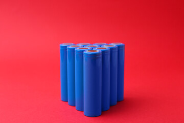 Many AA cell batteries on red background, closeup
