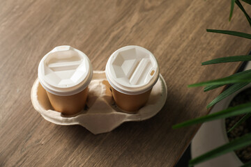 Holder with paper cups on wooden table, above view. Mockup for design