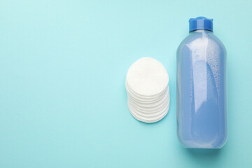 Clean cotton pads and micellar water on light blue background, top view. Space for text