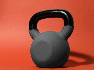 One metal kettlebell on coral background, closeup. Sports equipment