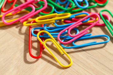 Many colorful paper clips on wooden table, closeup