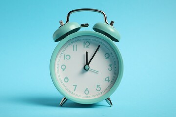 One turquoise alarm clock on light blue background