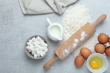 Rolling pin and ingredients for dough on light grey table, flat lay