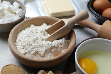 Ingredients for dough and rolling pin on light grey table, closeup