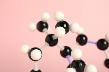 Molecule of retinol (vitamin A) on pink background, closeup. Chemical model