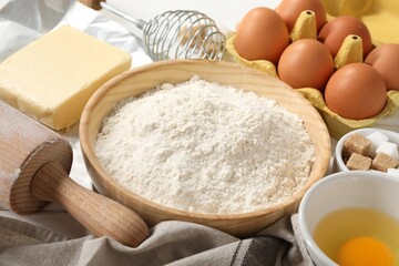 Rolling pin and ingredients for dough on table, closeup