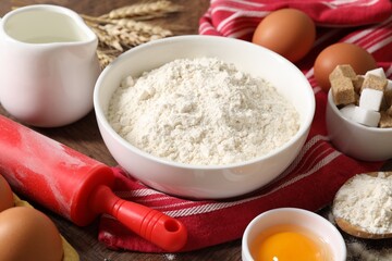 Rolling pin and ingredients for dough on table, closeup