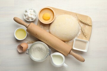Rolling pin and different ingredients on light wooden table, flat lay