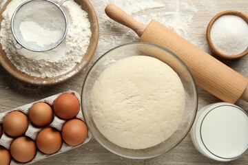 Rolling pin and different ingredients on light wooden table, flat lay