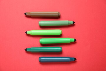 Many colorful markers on red background, flat lay