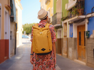 Fototapeta premium Woman in dress strolls through colorful streets of Spanish coastal town of La Vila Joiosa or Villajoyosa. sunny winter atmosphere highlights charm of Mediterranean architecture and quiet seaside life