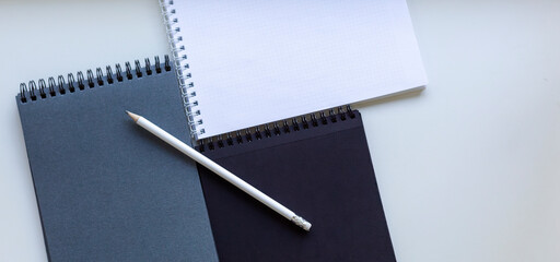 Spiral notebooks and pencil on white desk. 