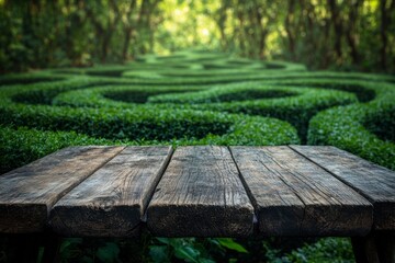 Close-up of an empty rustic wooden table with a blurred green bush maze in the background.