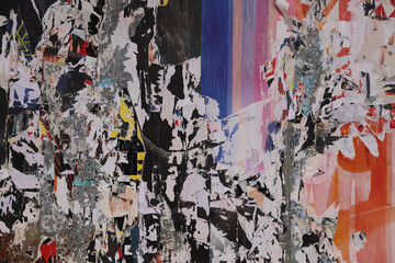 Fototapeta premium scraps wall covered in layers of ad posters, featuring a striking of paint torn paper Old ripped torn posters textures backgrounds grunge creased vintage collage placards empty space backdrop surface