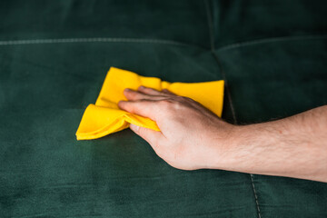 Man cleans sofa with soft wipe. Couch cleaning.