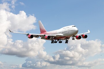 Commercial airplane flying in blue sky, preparing for landing.
