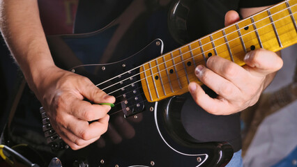 A close-up of a person playing an electric guitar, focusing on their hands and the guitar strings....