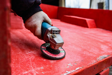 Rebuilding upgrading and modifying trailer. Man grinding old paint from trailer.