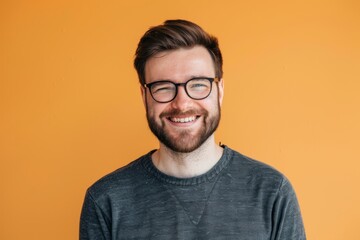 Portrait of a content man in his 30s smiling at the camera over soft orange background