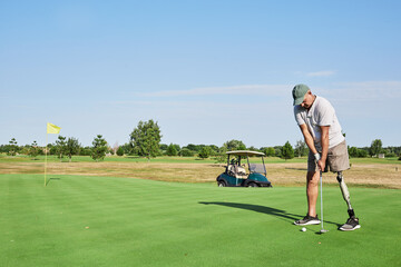 Golfer focusing on his swing while standing on the green, demonstrating skill and determination at a scenic golf course