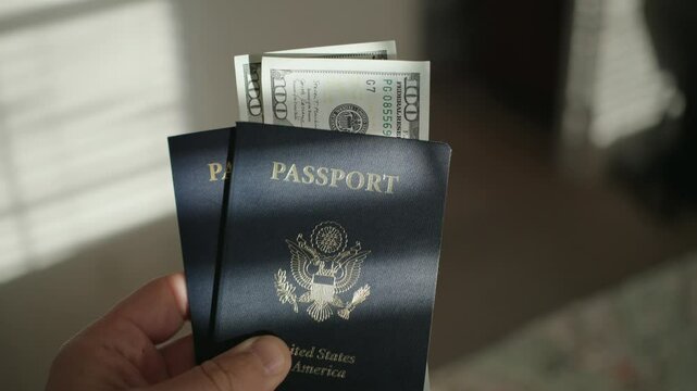 Holding two American passports with 100 dollar bills 