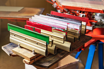 silk screen printing. silkscreen textile printery. manual screen printing. squeegees on wooden shelve of the print screening apparatus