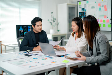 Asian entrepreneurs working together in a modern office, analyzing financial charts and reports displayed on a laptop