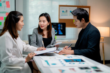 Asian businesspeople working together in modern office analyzing financial reports and discussing company strategy