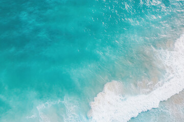 Obraz premium Aerial view of crystal-clear turquoise ocean waves rolling onto a soft sandy beach. 