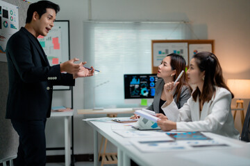 Asian businessman using pencil presenting company marketing data to team in meeting room