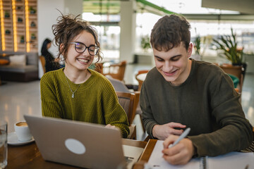 young couple work together and learn on laptop at cafe