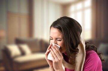 Sick young sad woman with cold and blowing nose