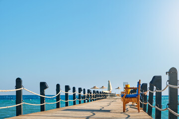 Obraz premium Wooden pier on sea stretching into distance beyond horizon on sunny summer day. Vacation and Travel Concept.