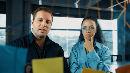 Professional business people discuss about creative marketing idea in modern office. Business team working together to brainstorm financial plan by using sticky notes on glass board. Manipulator.