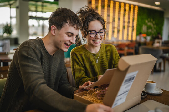 two students man and woman couple at cafe open post package box
