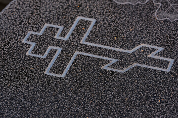sandblast engraved orthodox cross in black granite covered with frost