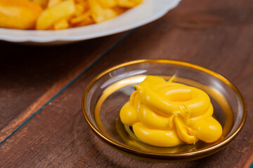 French fries and golden nuggets with cheese sauce on a wooden table
