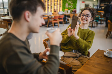 girlfriend use mobile phone to filming video of her boyfriend at cafe