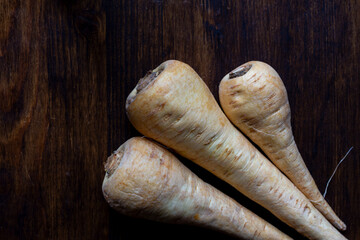 Aerial view of three parsnips on a wooden table, horizontal with copy space