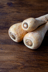 Top view of three parsnips on wooden table, vertical with copy space
