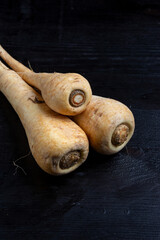 Top view of parsnips on dark wooden table, vertical with copy space