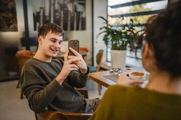 boyfriend use mobile phone to take a photo of his girlfriend at cafe