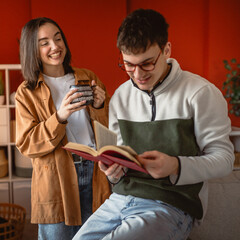 man enjoy and smile while read a book at home while woman bring coffee