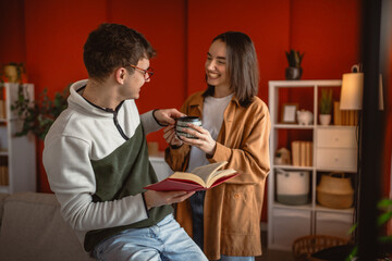 man enjoy and smile while read a book at home while woman bring coffee