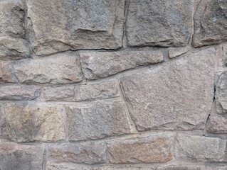 A grey stone wall with variable sized stones