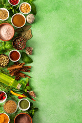 Fresh, fragrant spices and herbs arranged in an array of colors, sitting on a soft green backdrop,...