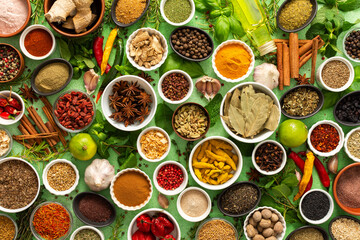 A vibrant assortment of fresh, multicolored spices and herbs on a delicate green background, perfect for cooking and culinary inspiration